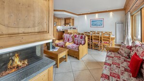 Um quarto aconchegante com lareira, móveis de madeira e uma área de jantar com cadeiras e mesa.