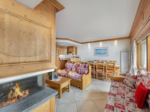 A cozy room with a fireplace, wooden furniture, and a dining area with chairs and a table.