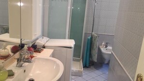 Et badeværelse med vask, spejl og bruseområde.