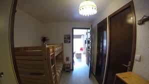 A narrow hallway with bunk beds on the left, a wooden bench on the right, and a door at the end. - Studio cabin for 4 people, south-facing, balcony (Valloire)