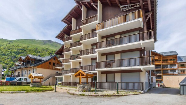 A multi-story hotel with balconies, a covered entrance, and a mountainous backdrop. - Studio cabin for 4 people, south-facing, balcony (Valloire)