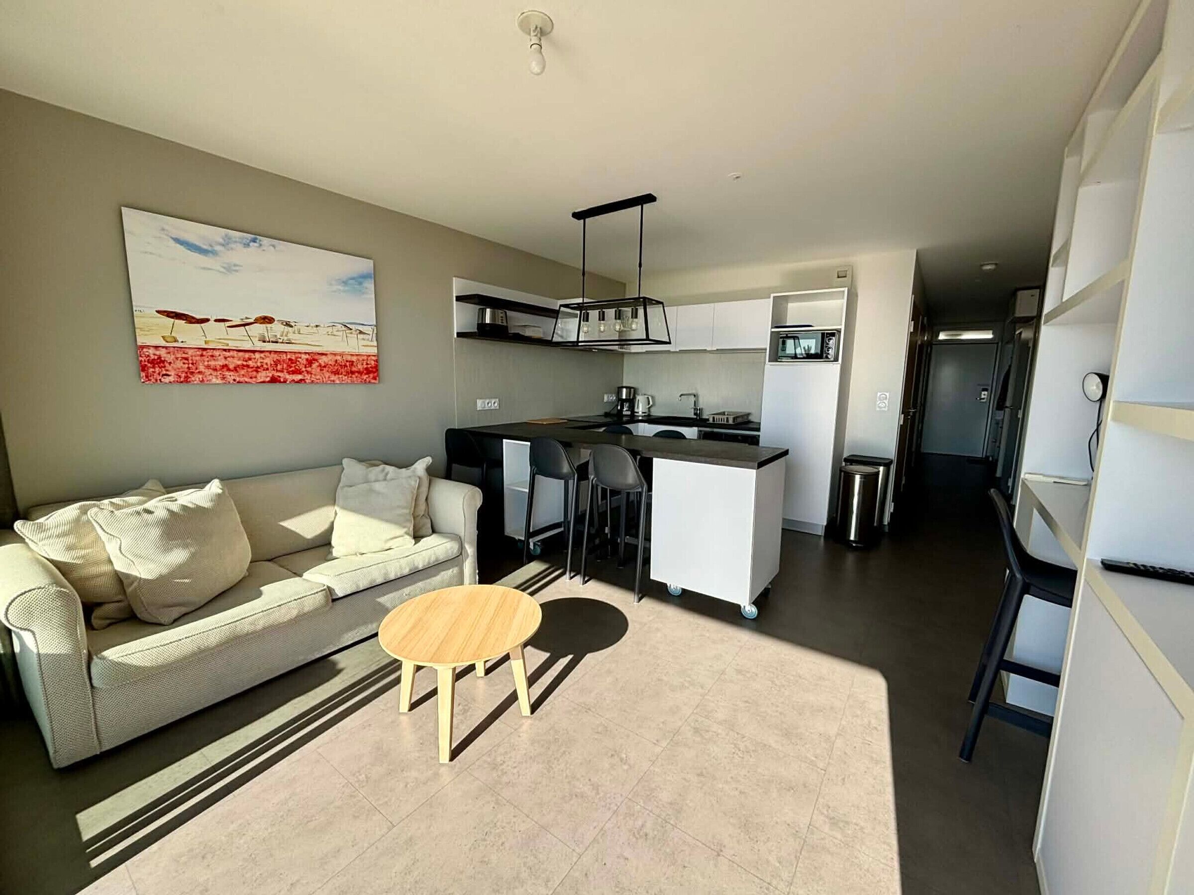 A modern apartment with a living area, kitchenette, and a dining area.