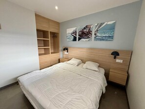 A bedroom with a bed, wooden wardrobe, and two wall-mounted lamps. - Stunning apartment for 6 with balcony, heated pool and direct beach access in La Tranche (La Tranche-sur-Mer)