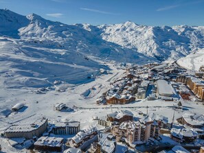 Uma cidade nas montanhas coberta de neve, com pistas de esqui e edifícios.