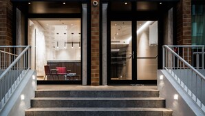 Entrada de hotel con una escalera, un comedor con sillas rojas y un diseño interior moderno.