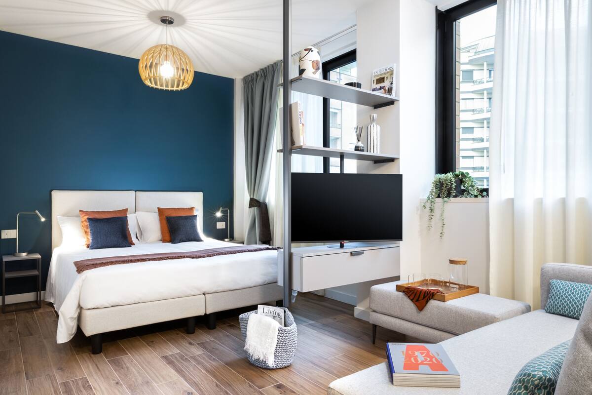 A modern bedroom with a bed, TV, and seating area.