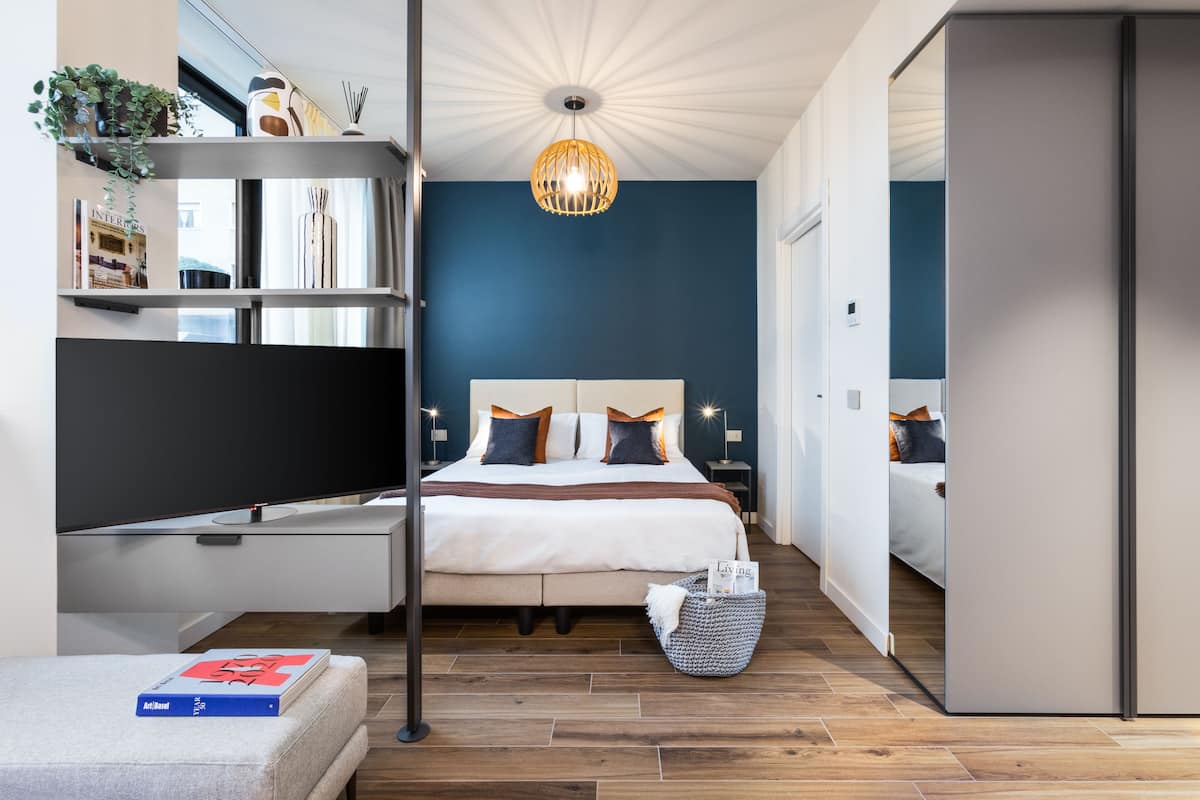 A modern bedroom with a bed, bedside tables, a TV, and a hanging light fixture.