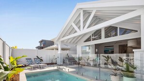 A modern outdoor pool area with a glass enclosure, lounge chairs, and potted plants. - Gone Coastal - Kingscliff (Kingscliff)