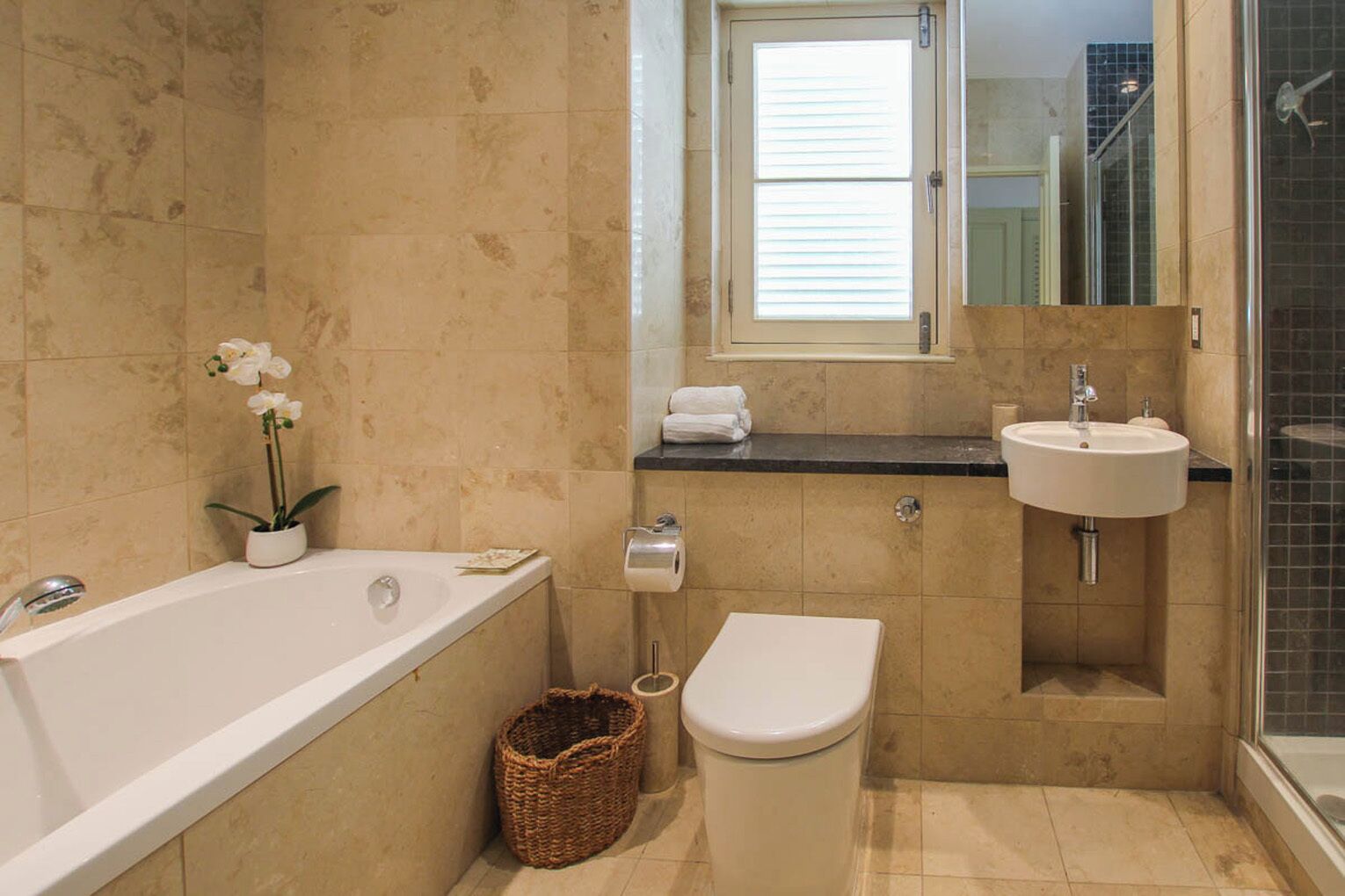 A bathroom with a bathtub, toilet, sink, and a shower area.
