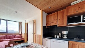 Tunnelmallinen keittiö, jossa on puiset kaapit, mikroaaltouuni ja astianpesukone. Ruokapöytä on katettu lautasilla, laseilla ja aterimilla.