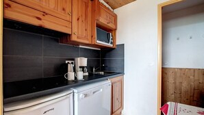 Kompakti keittiö, jossa on puukaapit, mikroaaltouuni, kahvinkeitin ja astianpesukone.