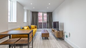A modern living room with a yellow sofa, wooden coffee table, and a TV on a wooden stand. - Stunning 2-bed Apartment in Camberley (Camberley)