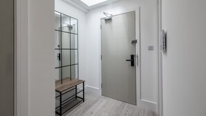A modern bathroom with a skylight, a glass shower enclosure, and a wooden bench. - Impeccable 2-bed Apartment in Camberley (Camberley)
