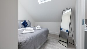 A bedroom with a bed, a large mirror, and a skylight. - Impeccable 2-bed Apartment in Camberley (Camberley)