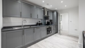 Una cocina moderna con gabinetes grises, un lavamanos de acero inoxidable y un horno empotrado.