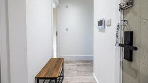 Un pasillo con un banco de madera, una puerta con cerradura de seguridad y un portero automático en la pared.