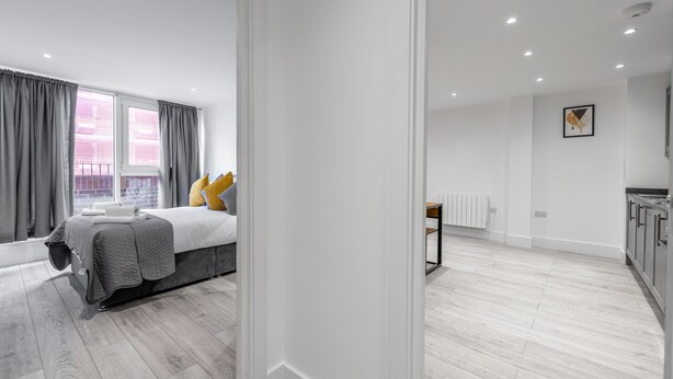 Un dormitorio moderno con una cama, una mesita de noche y una ventana con cortinas.