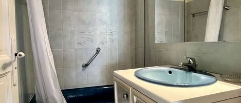 A bathroom with a shower, a sink, and a mirror.