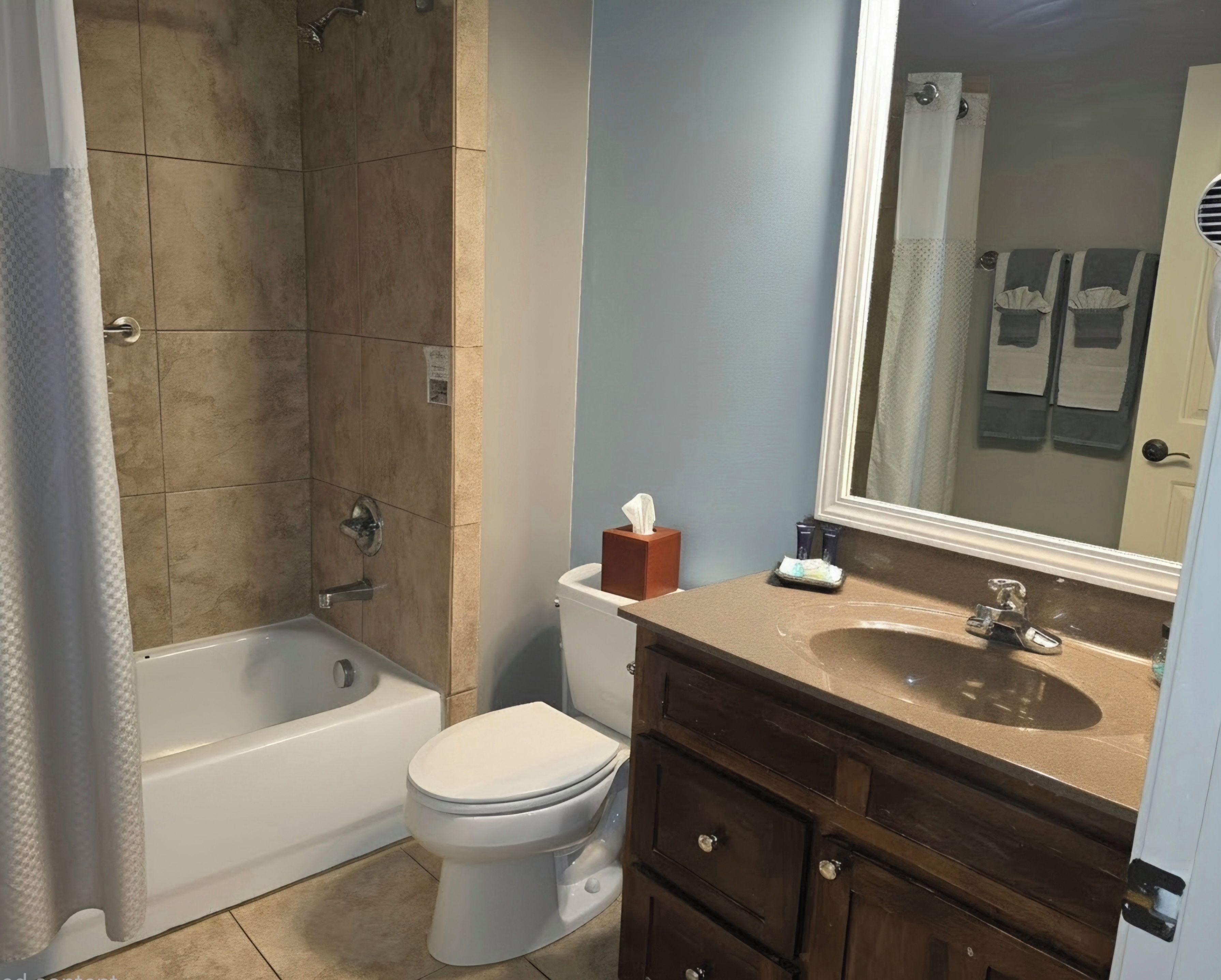 A bathroom with a bathtub, toilet, vanity, and a mirror.