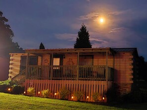 A cabin with a balcony, a small porch, and a visible door.