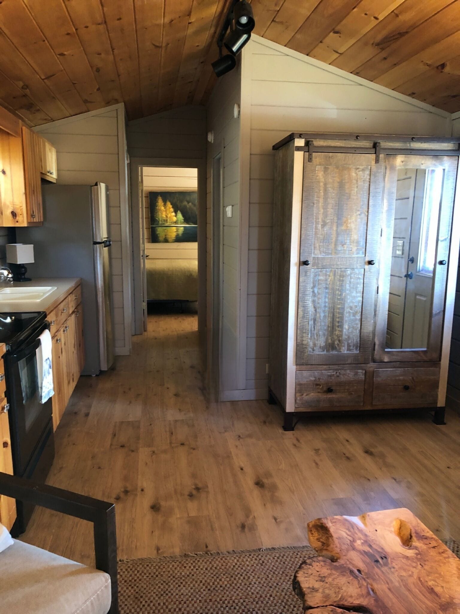 Una cocina compacta con armarios de madera, un refrigerador y un comedor con mesa de madera.