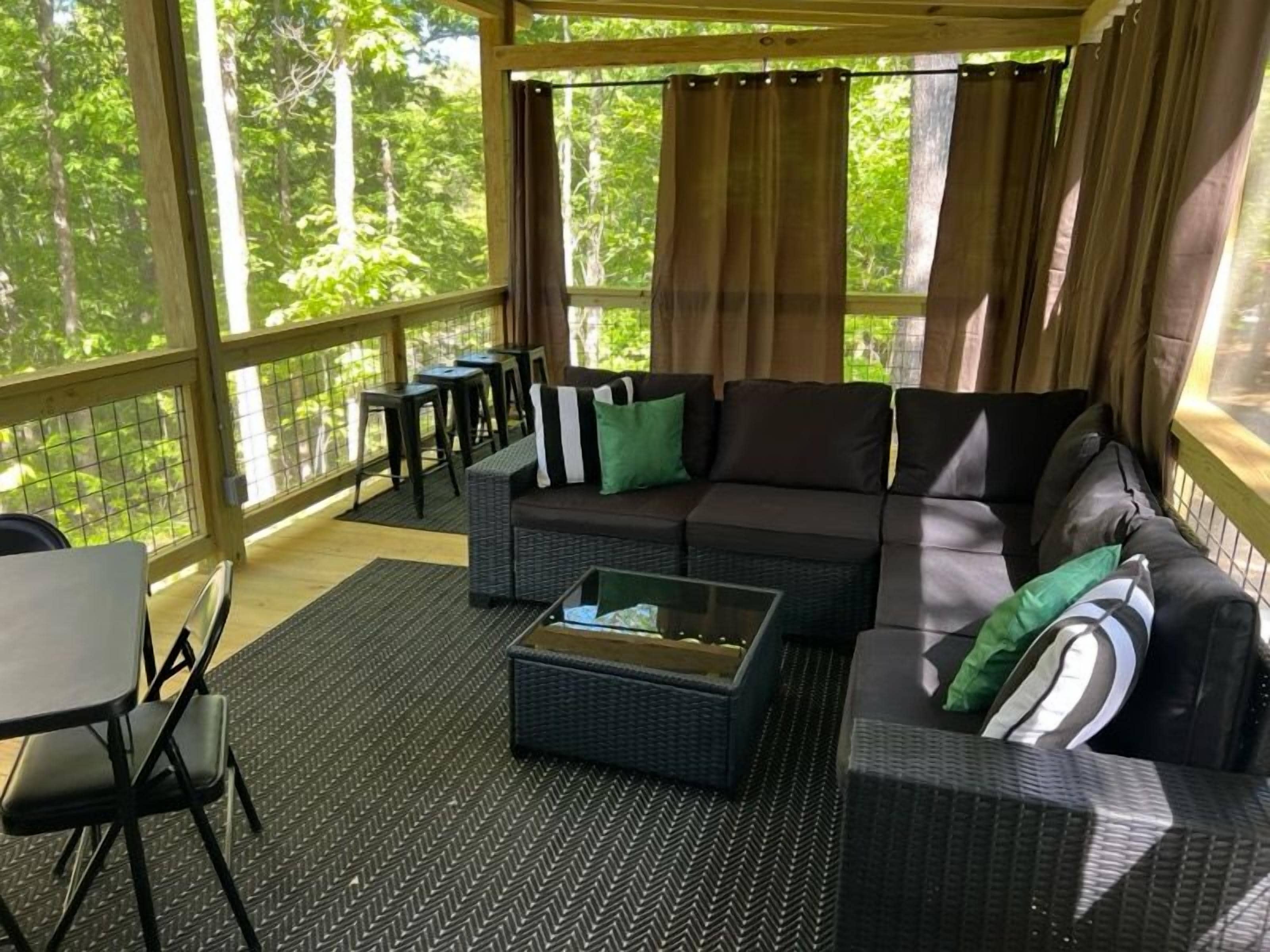 Un espacio de estar al aire libre techado con sofá, sillas y una mesa.