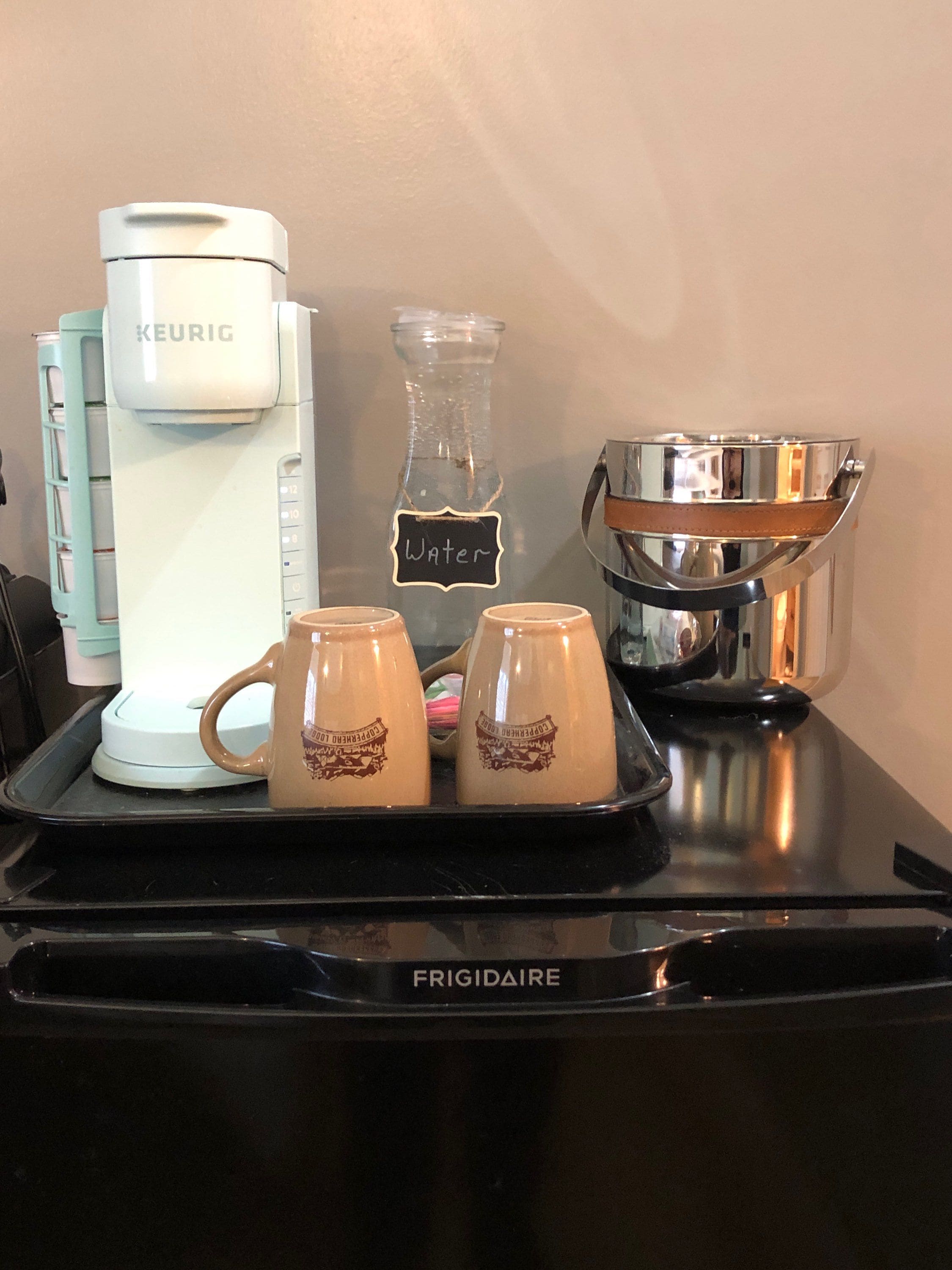 Une machine à café, une carafe d’eau et deux tasses sur un plateau.