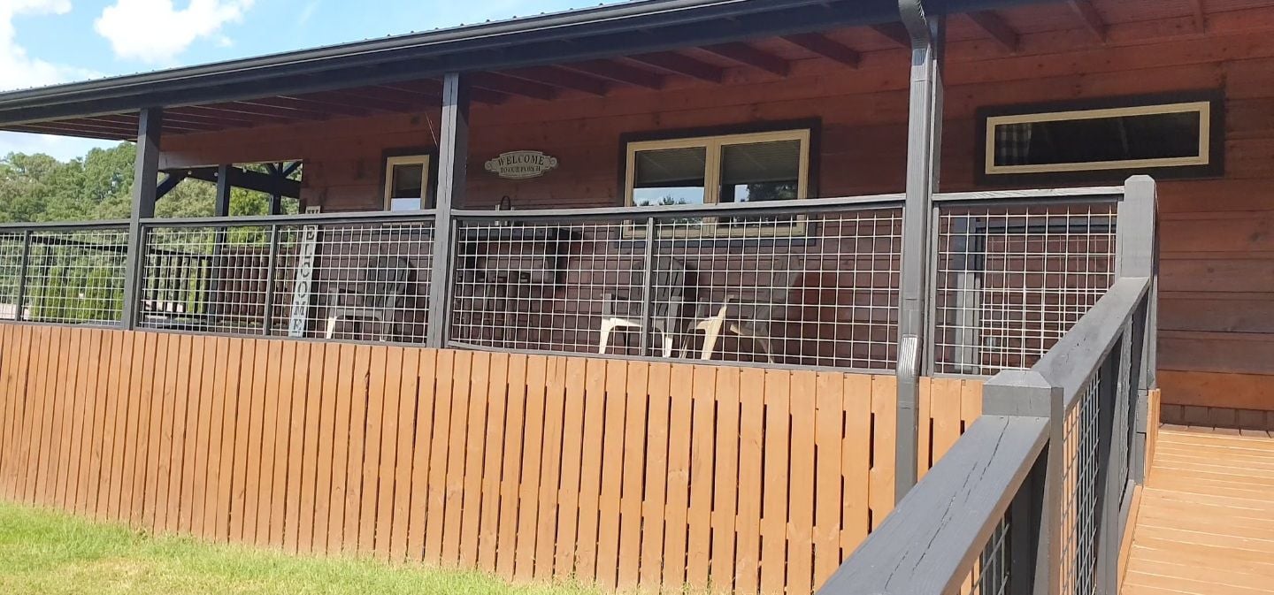 A wooden building with a fenced area, a wooden deck, and a sign that reads 'WELCOME'.