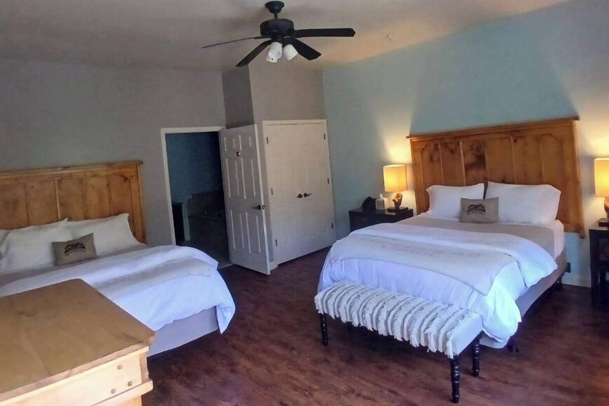 A bedroom with two beds, a wooden headboard, a ceiling fan, and a nightstand with a lamp.