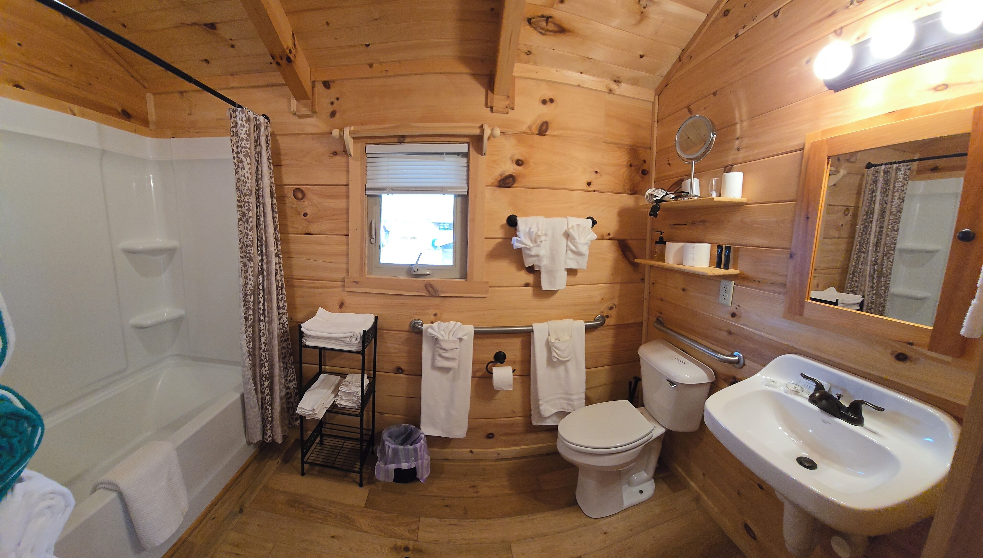 Bagno di una baita in legno con vasca, water e lavandino.