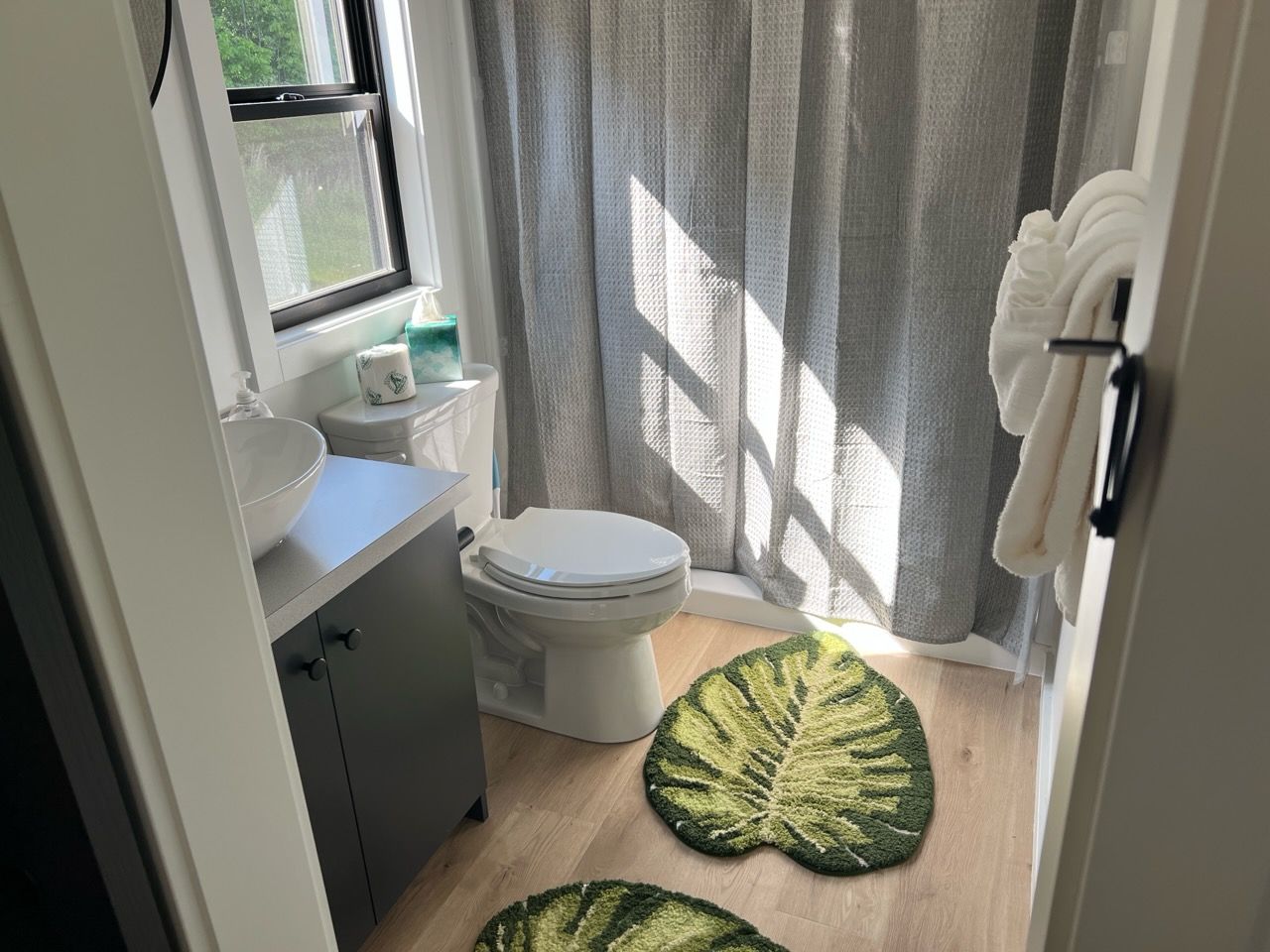 A bathroom with a toilet, sink, and a window with curtains.