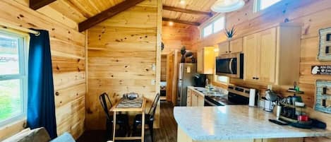 Ein Holzblock-Interieur mit Essbereich, Küche und einem großen Fenster.
