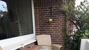 Un patio con mobili in vimini, un tavolino e una finestra.