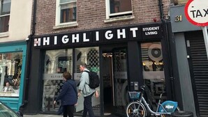 A building with a sign for 'HIGHLIGHT Student Living' and a 'TAX' sign nearby.