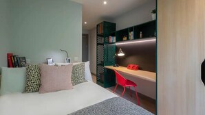 A bedroom with a bed, a desk, a chair, and a bookshelf.