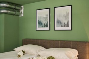 Un dormitorio con una cama, almohadas, un cabecero y dos cuadros en la pared.