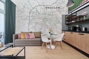 Una sala moderna con sofá, mesa de comedor y sillas, una cocina con armarios y electrodomésticos, además de un gran mapa mural.