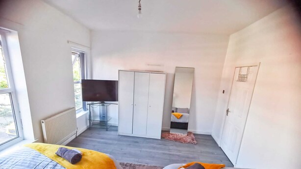 Une chambre moderne avec deux lits, une télévision, une armoire et un grand miroir.