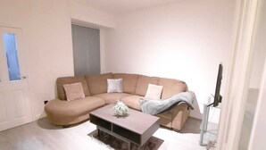 Un salon avec un canapé d’angle beige, une table basse et un téléviseur.