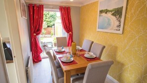 Un coin repas avec une table en bois, des rideaux rouges et un mur décoré sur le thème de la plage.