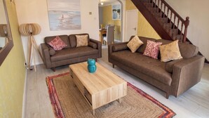 Un salon avec deux canapés marron, une table basse en bois et un tapis à motifs.