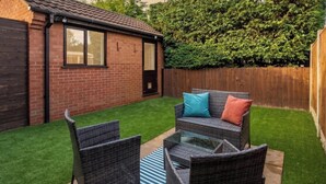 Un jardin avec un ensemble de mobilier de patio, une maison en briques et une clôture en bois.