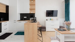 A modern kitchen with white cabinets, a wooden island, and a bar area. - Modern Apartment in Praga | Parking and Balcony (Warszawa)