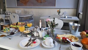 Un esmorzar amb diferents aliments, com ara pa, fruita i begudes, presentats sobre una taula amb un quadre al fons.