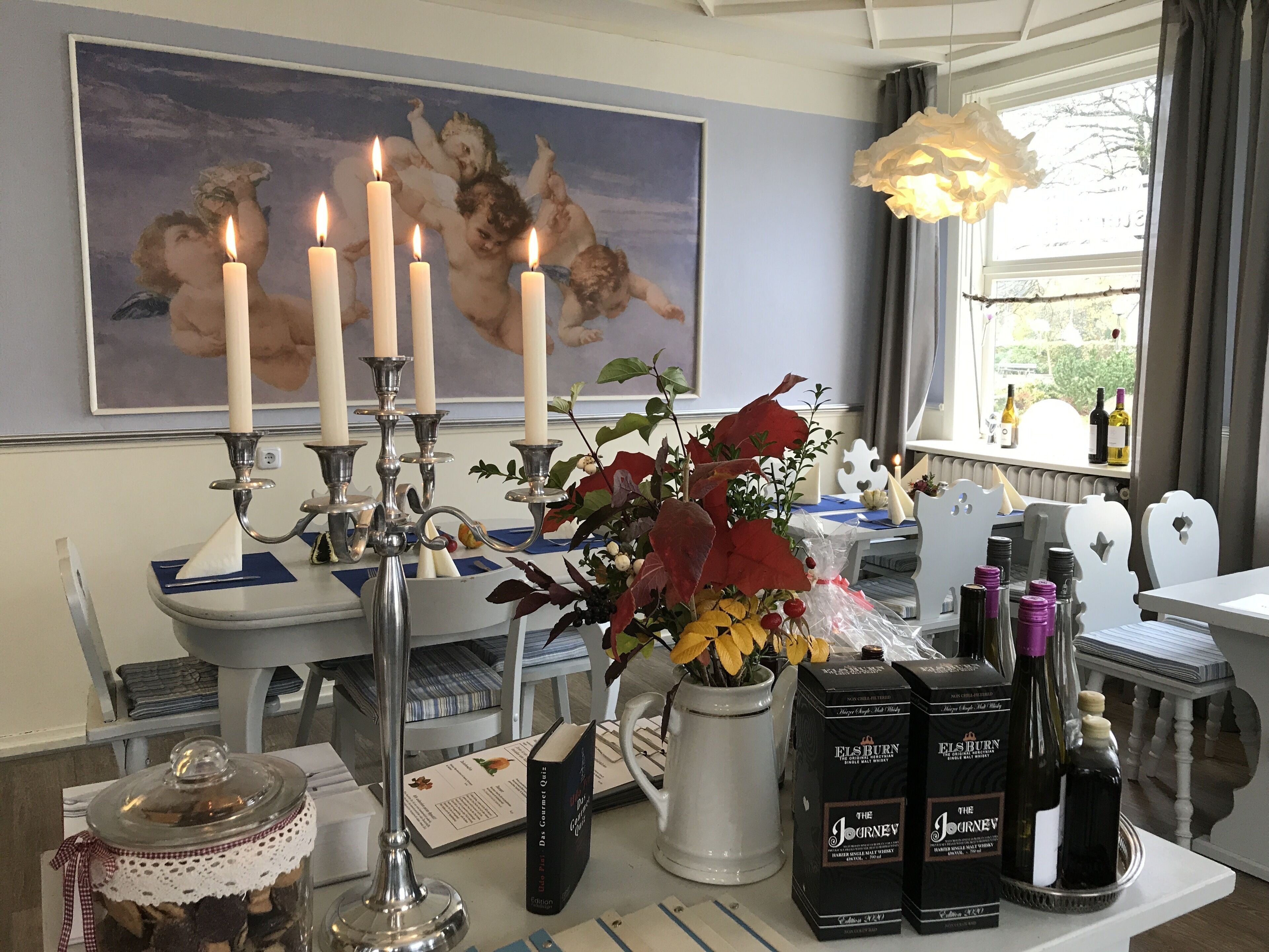 Un comedor con un candelabro, velas, un jarrón con flores y botellas de The Jorneyer wine.