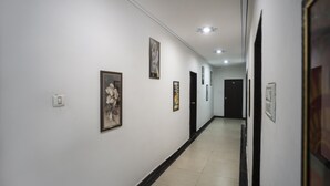 Un couloir aux murs blancs, orné de tableaux encadrés et doté d’une plinthe noire.