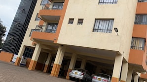 A multi-story residential building with a parking area in front. - Stay.Plus Hill View Studio Apartment (Nairobi)