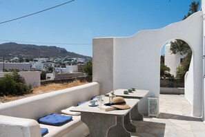 Une terrasse avec une table dressée pour deux personnes, d’où l’on peut admirer une ville aux bâtiments blancs et, au loin, une montagne.