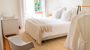 A bedroom with a bed, a chair, a wardrobe, and a window with a view of greenery outside. - Madeira Precious Penthouse (Funchal)