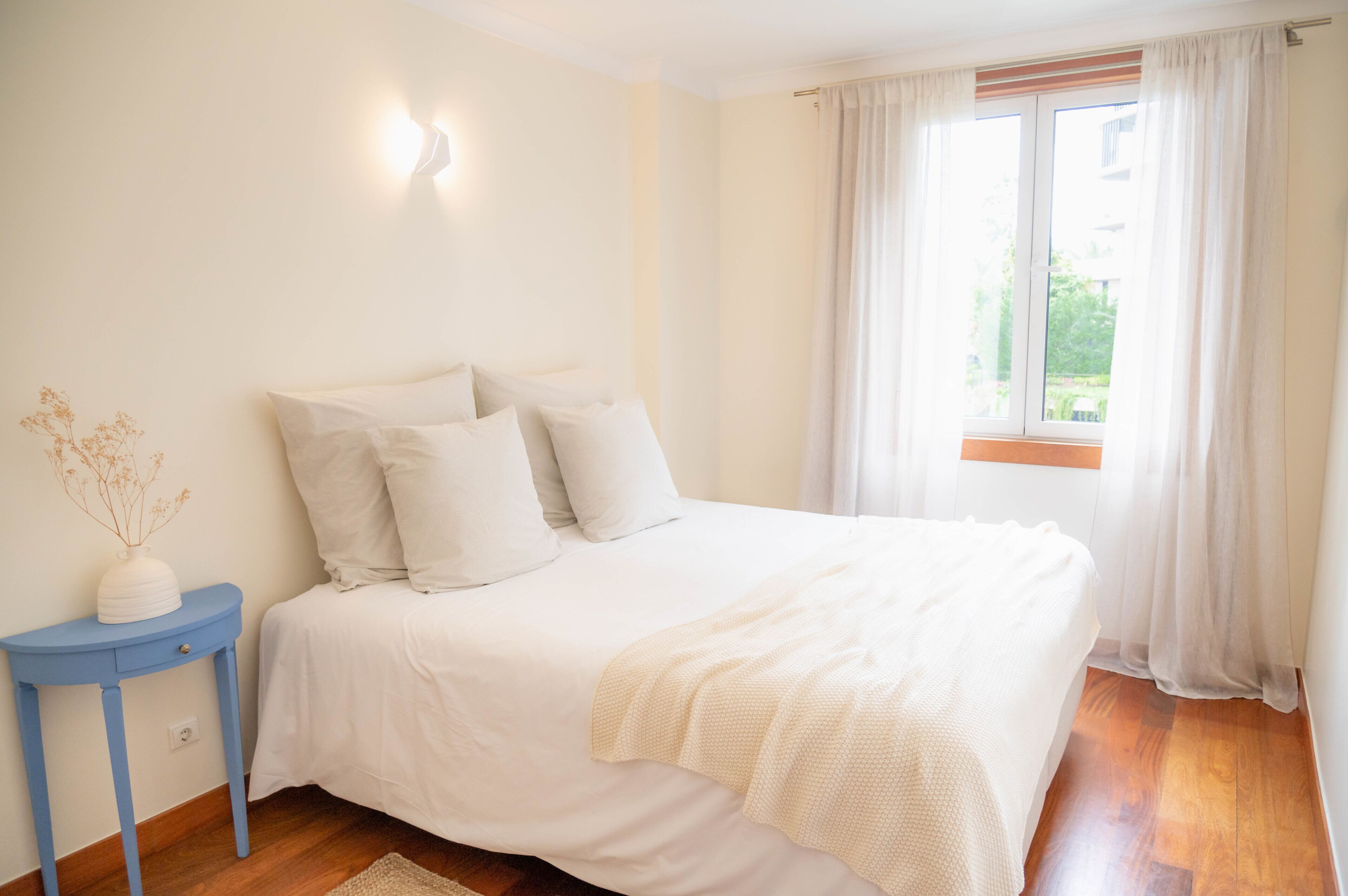 Une chambre à coucher avec un lit, une table de chevet et une fenêtre avec des rideaux.